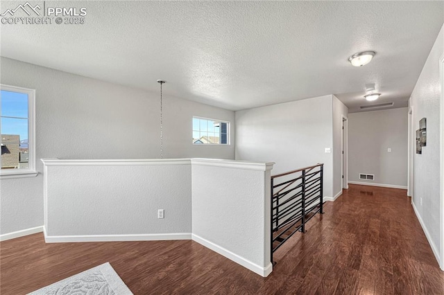 hallway featuring an upstairs landing, visible vents, baseboards, and wood finished floors