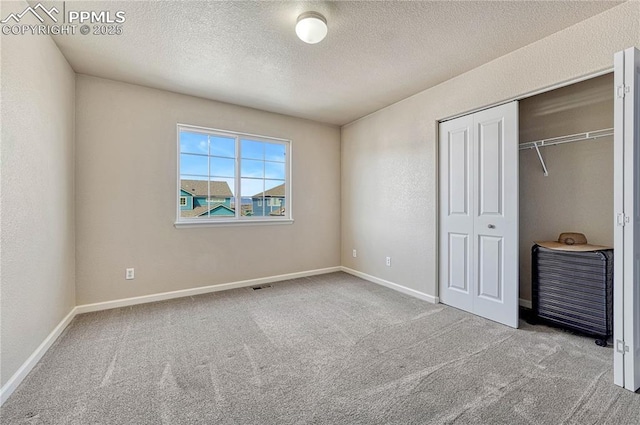 unfurnished bedroom featuring carpet flooring, visible vents, a closet, and a textured ceiling