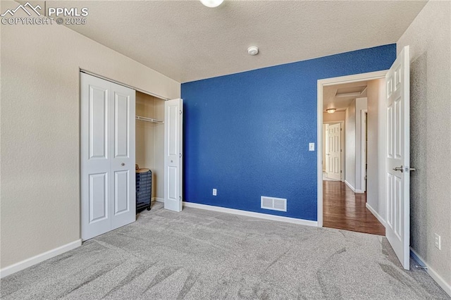 unfurnished bedroom with visible vents, baseboards, carpet, and a textured wall