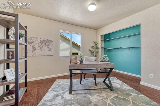 office space with wood finished floors, baseboards, a textured wall, and a textured ceiling