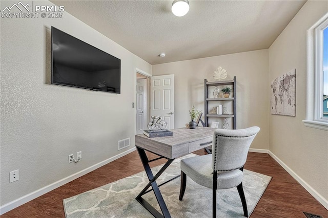 home office with visible vents, wood finished floors, baseboards, and a textured ceiling