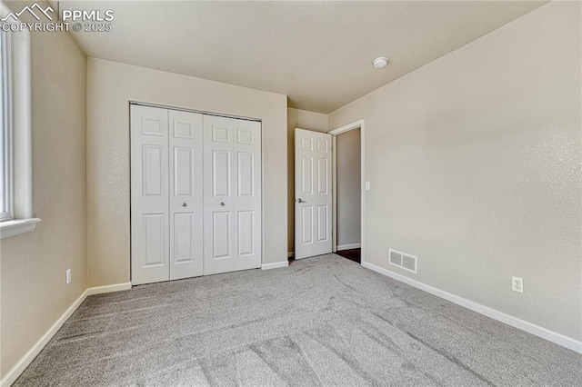 unfurnished bedroom featuring a closet, visible vents, baseboards, and carpet floors