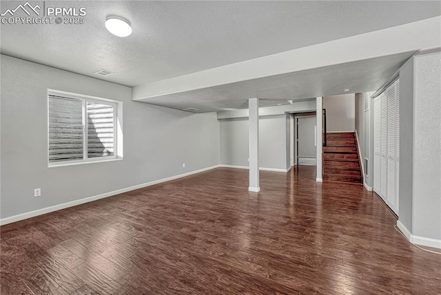 below grade area with visible vents, a textured ceiling, wood finished floors, baseboards, and stairs