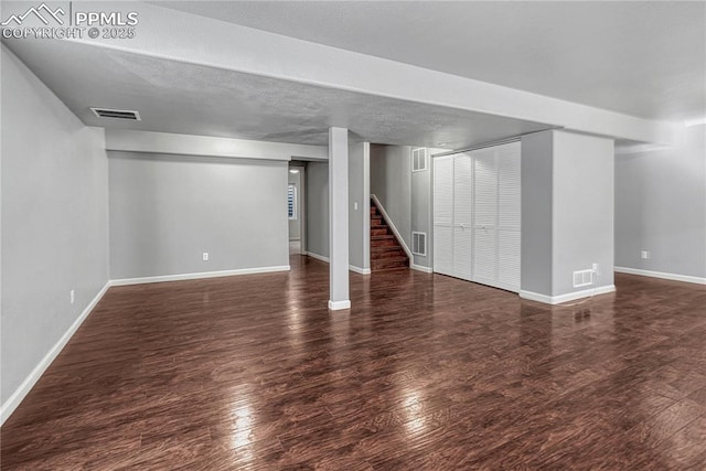 finished basement with visible vents, wood finished floors, and stairs