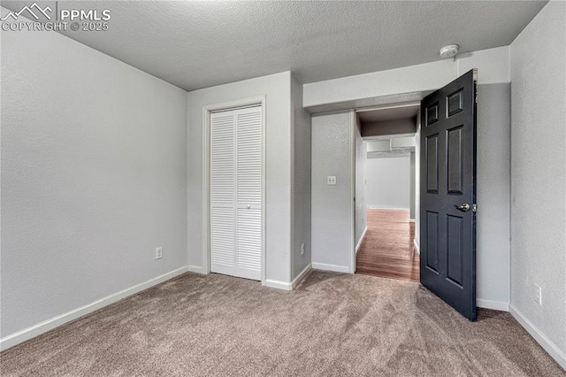 unfurnished bedroom with a closet, baseboards, a textured ceiling, and carpet flooring