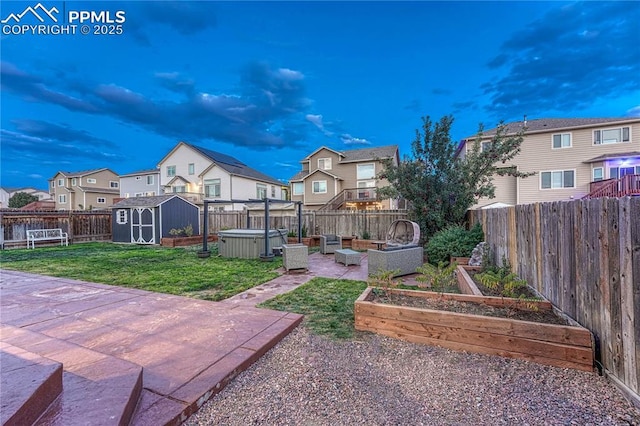 view of yard featuring a garden, a fenced backyard, a hot tub, a patio area, and a residential view