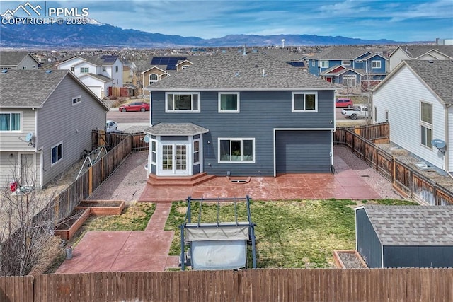 rear view of property featuring a residential view, a fenced backyard, a garden, a mountain view, and a patio