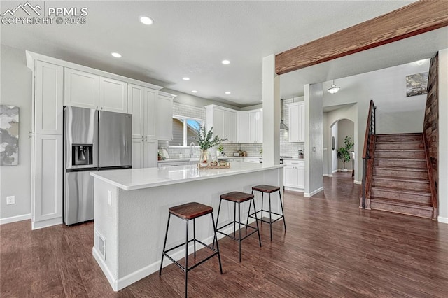 kitchen with tasteful backsplash, a kitchen island, stainless steel fridge with ice dispenser, dark wood-style floors, and white cabinetry