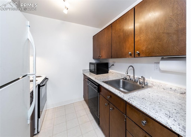 kitchen with baseboards, light countertops, rail lighting, black appliances, and a sink