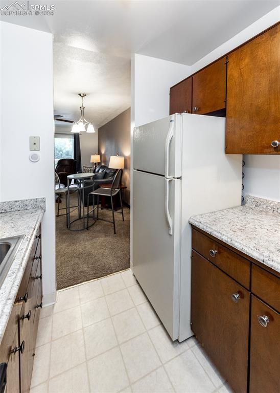 kitchen featuring open floor plan, light colored carpet, and freestanding refrigerator
