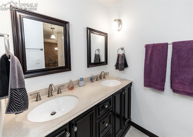full bathroom with double vanity, baseboards, and a sink
