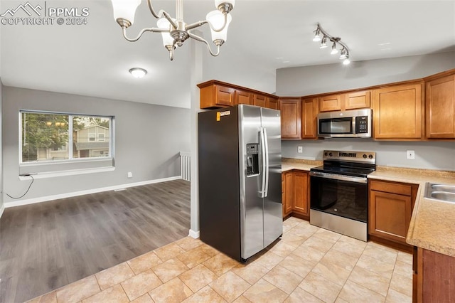 kitchen featuring appliances with stainless steel finishes, decorative light fixtures, vaulted ceiling, light hardwood / wood-style flooring, and an inviting chandelier