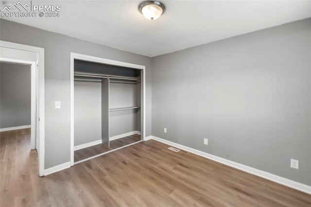 unfurnished bedroom with wood-type flooring and a closet