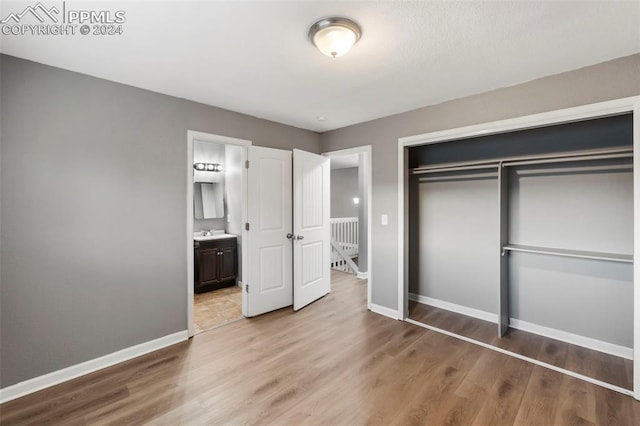 unfurnished bedroom featuring light hardwood / wood-style floors, a closet, sink, and connected bathroom