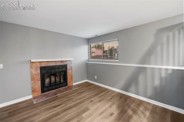 unfurnished living room with a tiled fireplace and wood-type flooring