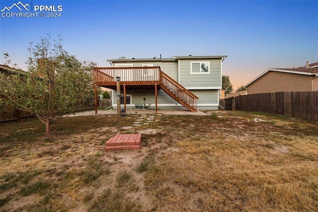 back house at dusk featuring a deck and a patio area