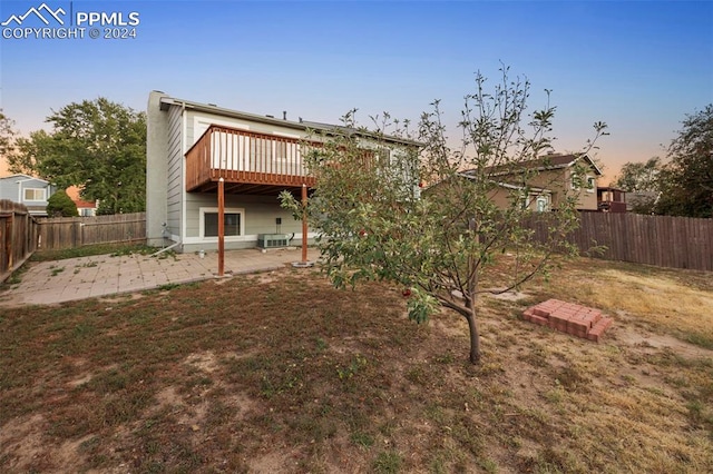 back house at dusk featuring a yard and a patio area