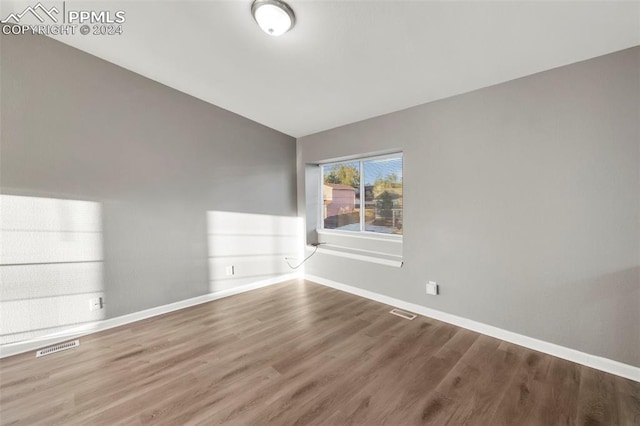 spare room with hardwood / wood-style flooring and vaulted ceiling