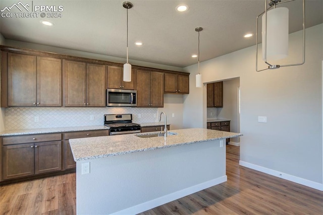 kitchen with backsplash, sink, appliances with stainless steel finishes, light hardwood / wood-style flooring, and light stone countertops