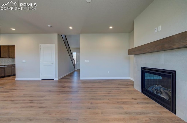 unfurnished living room with light hardwood / wood-style flooring and a tile fireplace