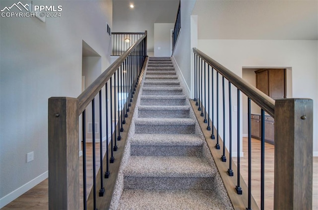 stairs featuring a high ceiling and wood-type flooring