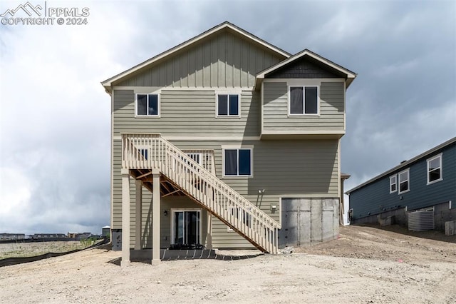 rear view of property with board and batten siding and stairway