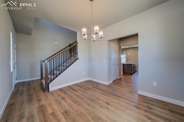 spare room featuring wood-type flooring and an inviting chandelier