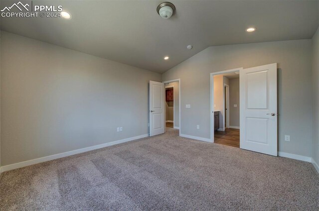 unfurnished bedroom with carpet flooring and lofted ceiling