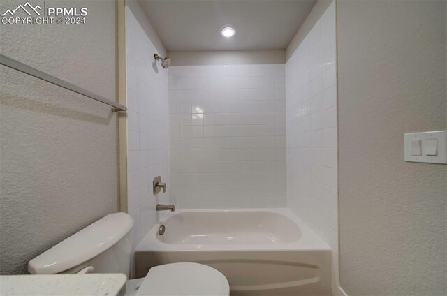 bathroom featuring tiled shower / bath combo and toilet