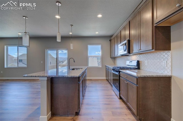 kitchen featuring sink, wood-type flooring, decorative backsplash, light stone counters, and stainless steel appliances