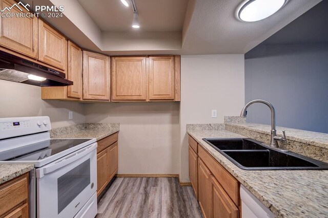 kitchen with white electric stove, track lighting, light stone countertops, hardwood / wood-style flooring, and sink