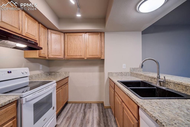 kitchen featuring under cabinet range hood, white electric range, a sink, light wood-type flooring, and a tray ceiling