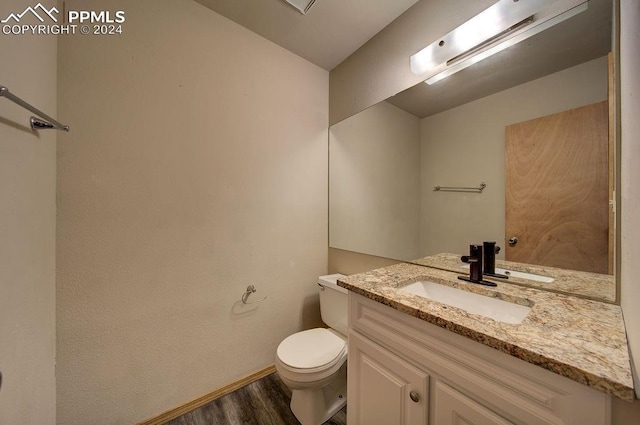 half bathroom featuring vanity, wood finished floors, toilet, and baseboards