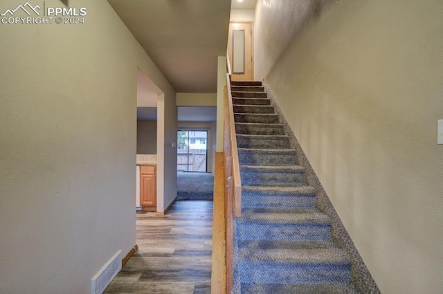 stairway with wood finished floors and visible vents