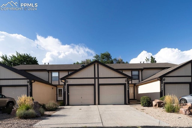 view of front of house with a garage, concrete driveway, and a shingled roof