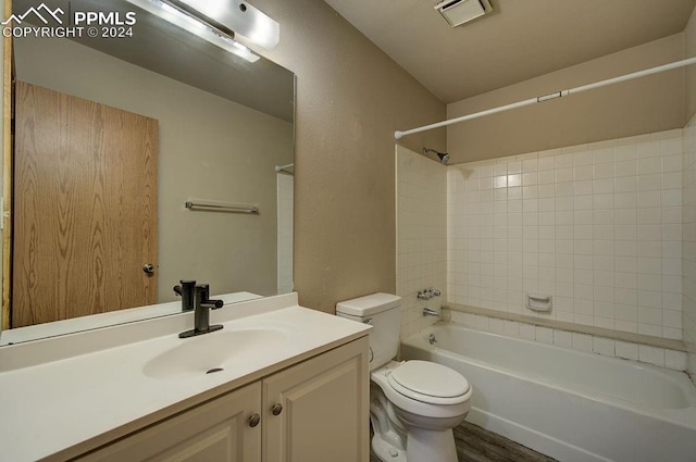 bathroom featuring visible vents, toilet, vanity, shower / tub combination, and wood finished floors