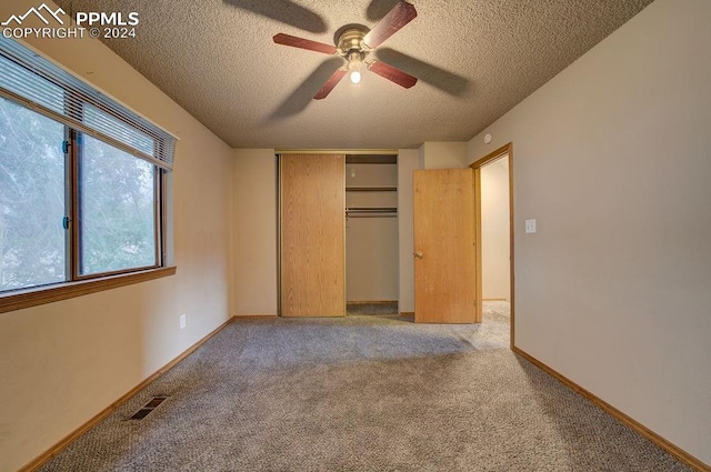 unfurnished bedroom featuring ceiling fan, light colored carpet, a closet, and a textured ceiling