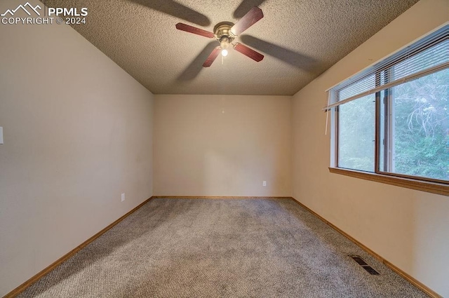 empty room featuring carpet, visible vents, a textured ceiling, and baseboards