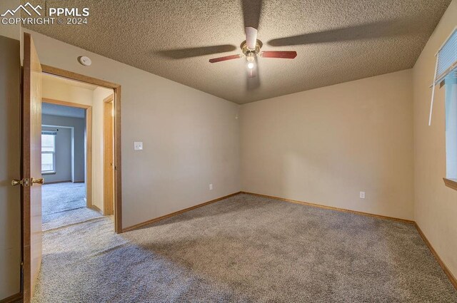 spare room with a textured ceiling, ceiling fan, and light carpet