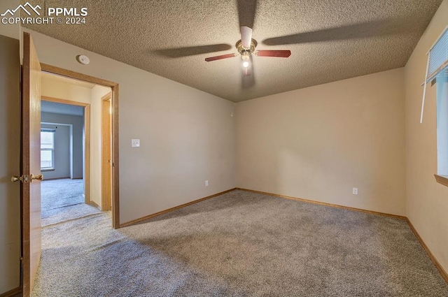 carpeted empty room featuring a textured ceiling, a ceiling fan, and baseboards