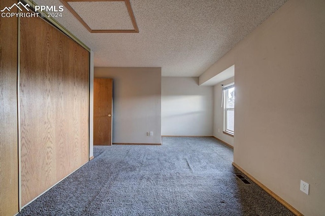 carpeted empty room with a textured ceiling