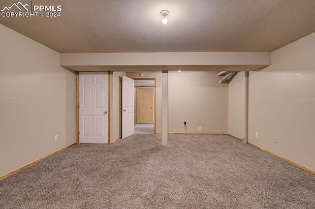 finished basement featuring a textured ceiling, carpet floors, and baseboards