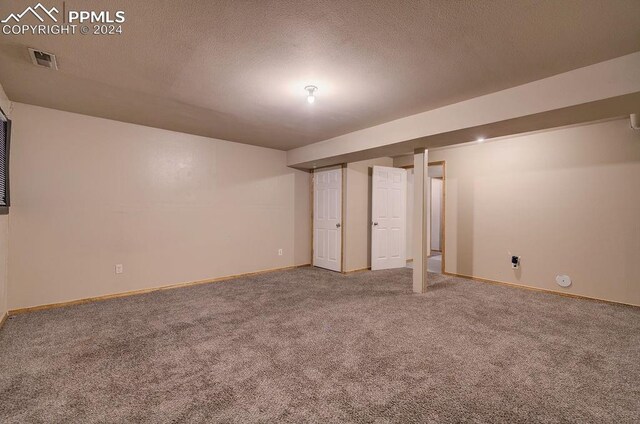 basement featuring carpet flooring and a textured ceiling