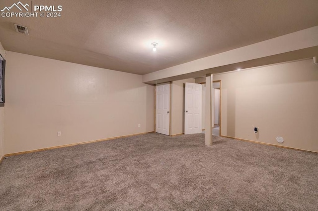 finished basement with baseboards, visible vents, a textured ceiling, and carpet flooring