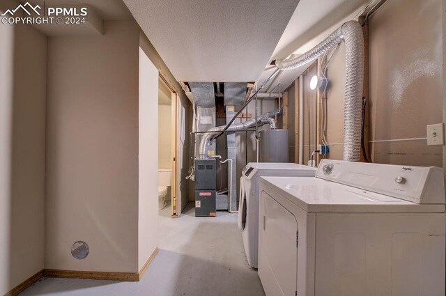 laundry area with gas water heater, a textured ceiling, heating unit, and independent washer and dryer