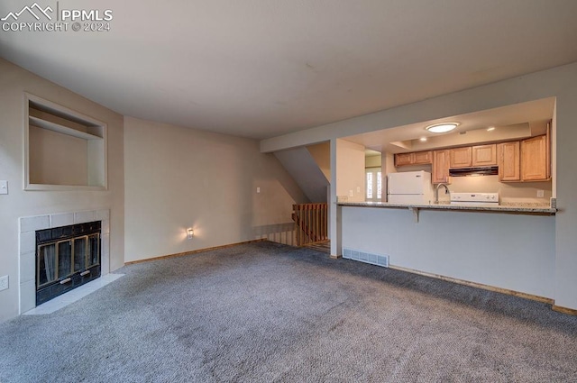 unfurnished living room with a tile fireplace, visible vents, baseboards, stairway, and carpet