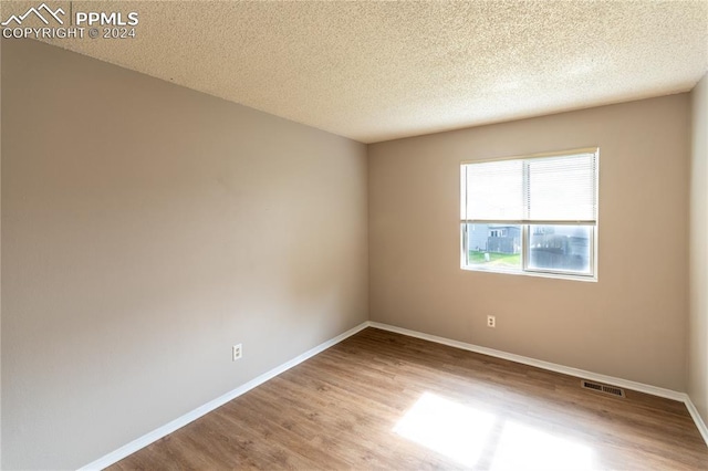 spare room featuring wood-type flooring and a textured ceiling