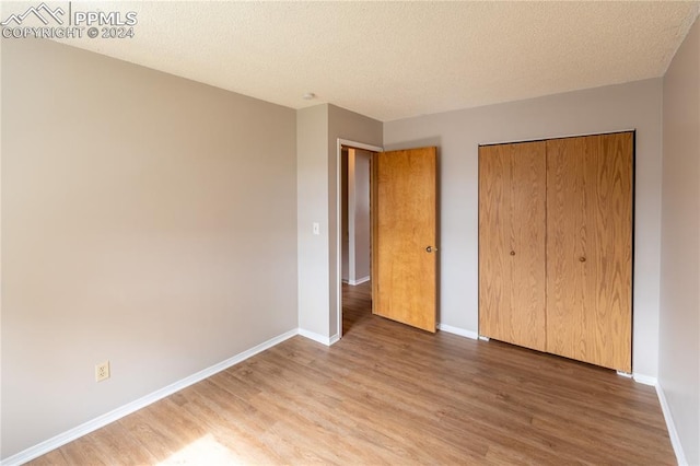 unfurnished bedroom featuring a textured ceiling, hardwood / wood-style floors, and a closet