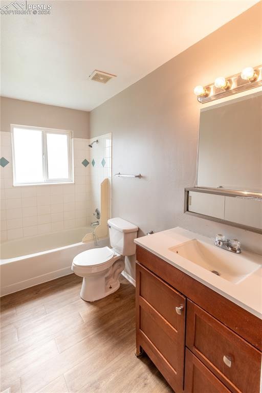 full bathroom with tiled shower / bath combo, vanity, and toilet