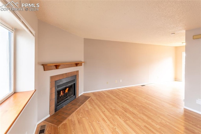 unfurnished living room with hardwood / wood-style flooring, a fireplace, and a textured ceiling